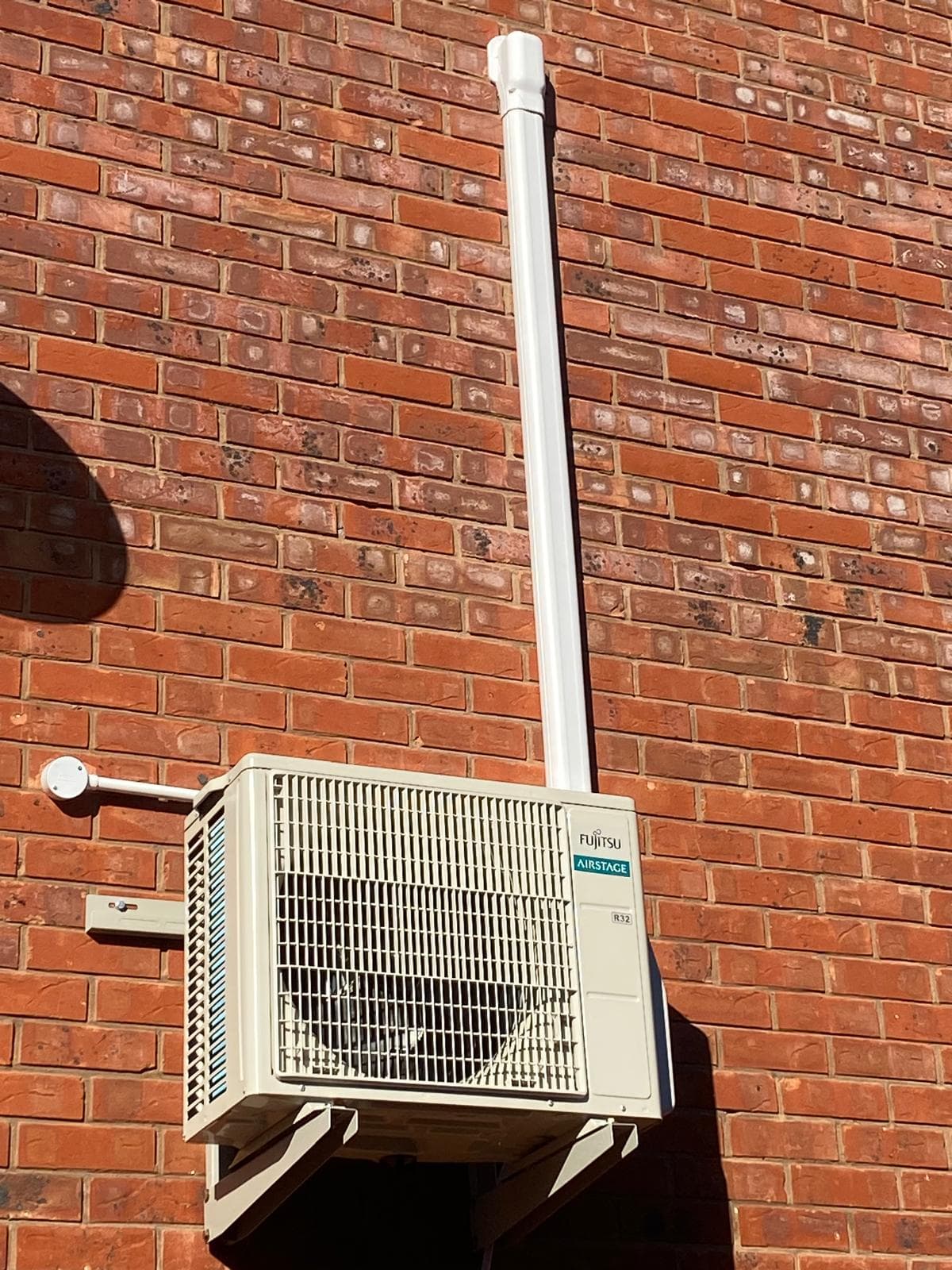 Fujitsu Airstage outdoor air conditioning unit mounted on a brick wall